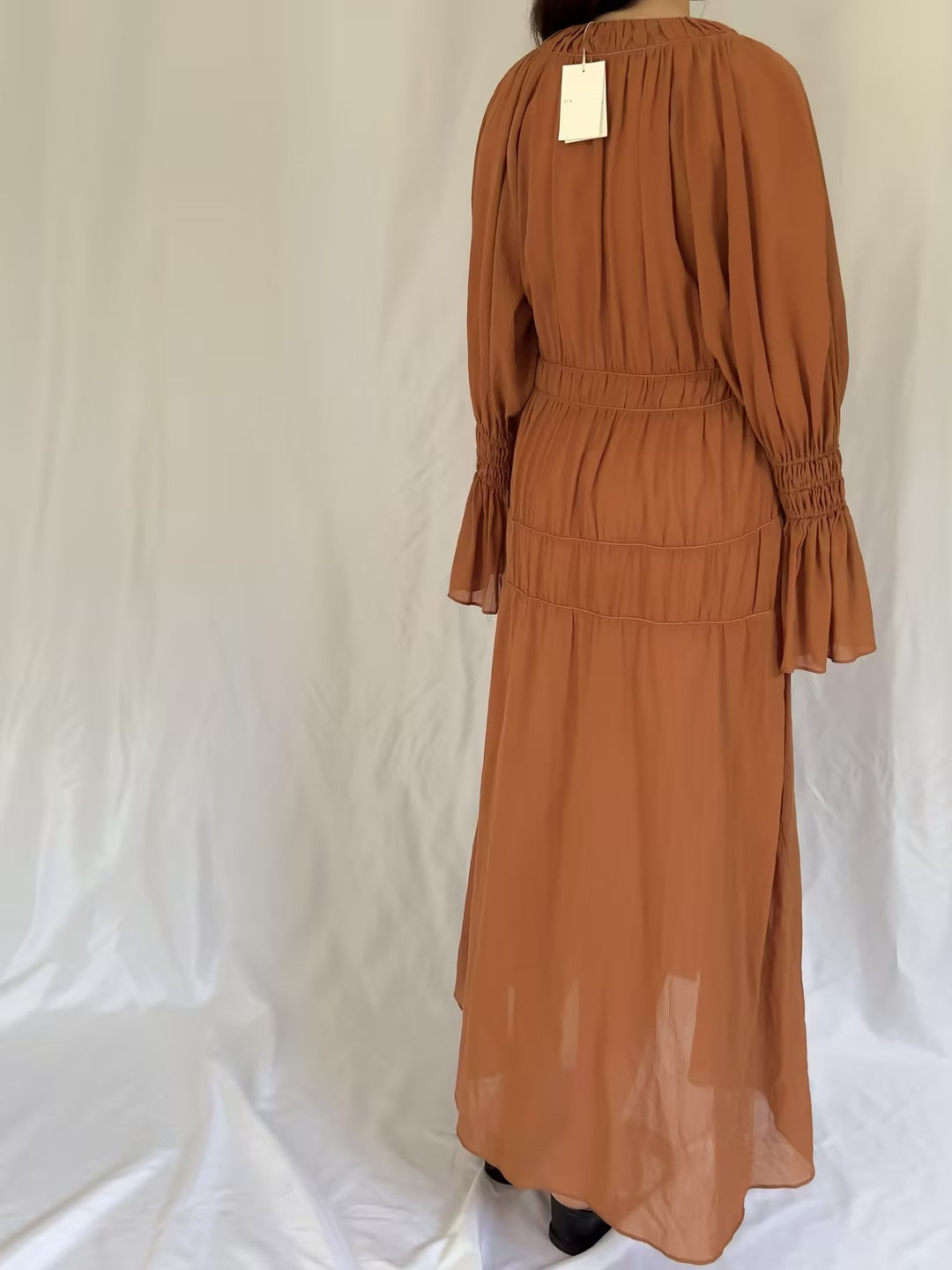 Brown dress with long sleeves and a fitted waist on a white background