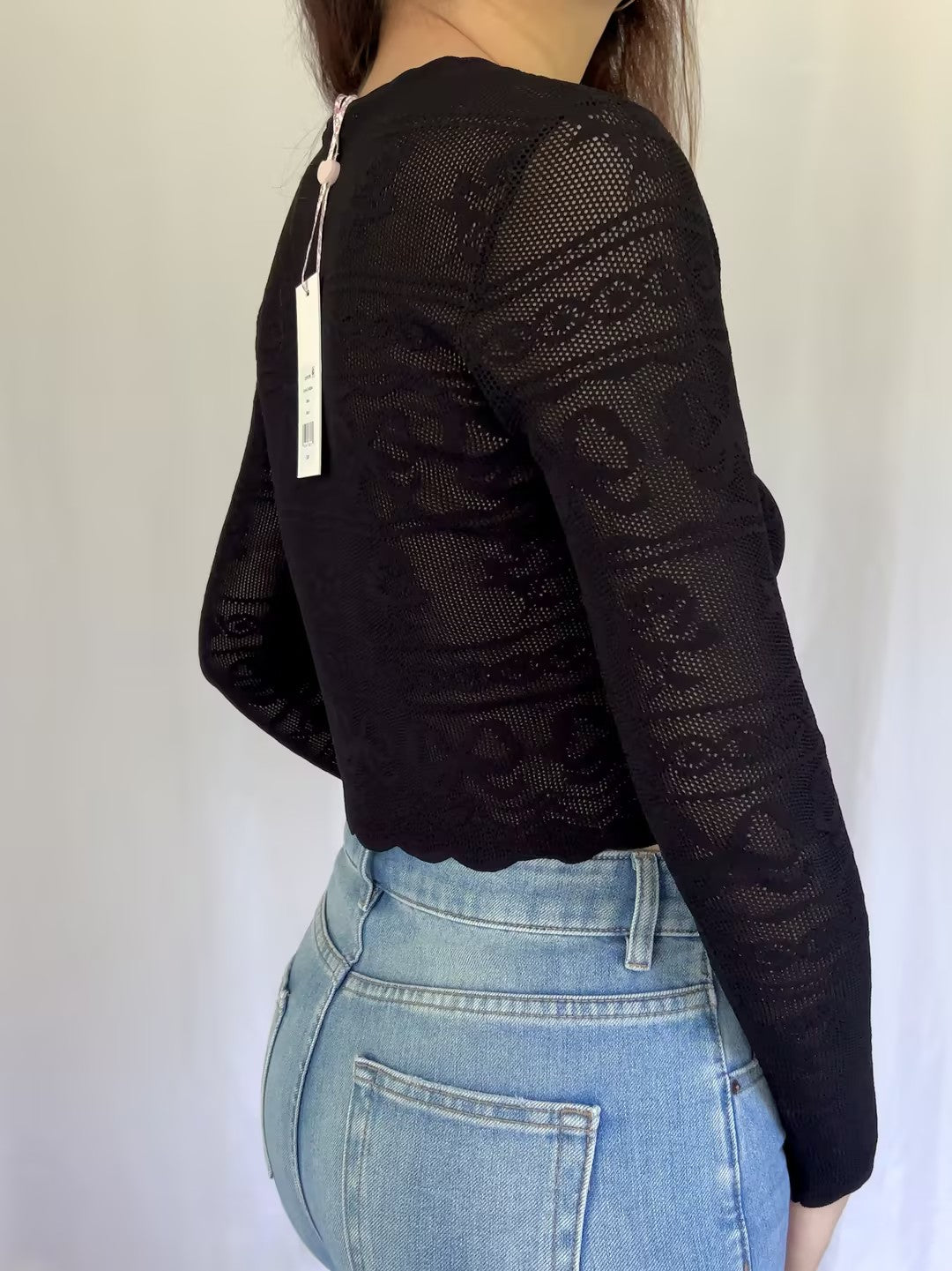 Black lace top worn by a person on a white background